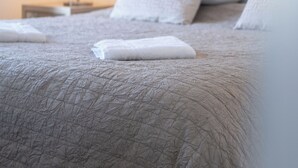 Siististi pedattu sänky, jossa on kuvioitu peitto ja tyynyjä, yöpöytälamppu ja yöpöytä.