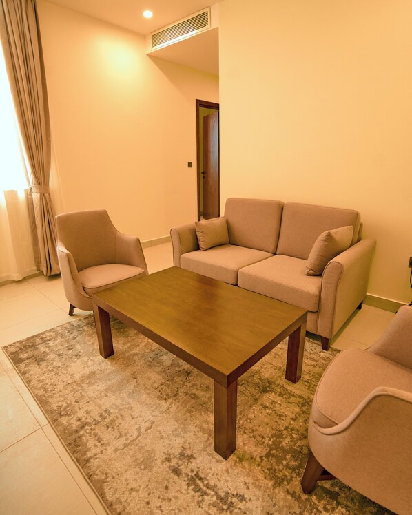A living room with a beige sofa, two armchairs, and a wooden coffee table. - ZABIBU HOTEL (Dodoma)