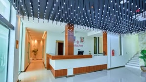 Ein Hotel-Rezeptionsbereich mit modernem Design, der einen Empfangstresen, eine Treppe und einen zur übrigen Etage führenden Gang zeigt.