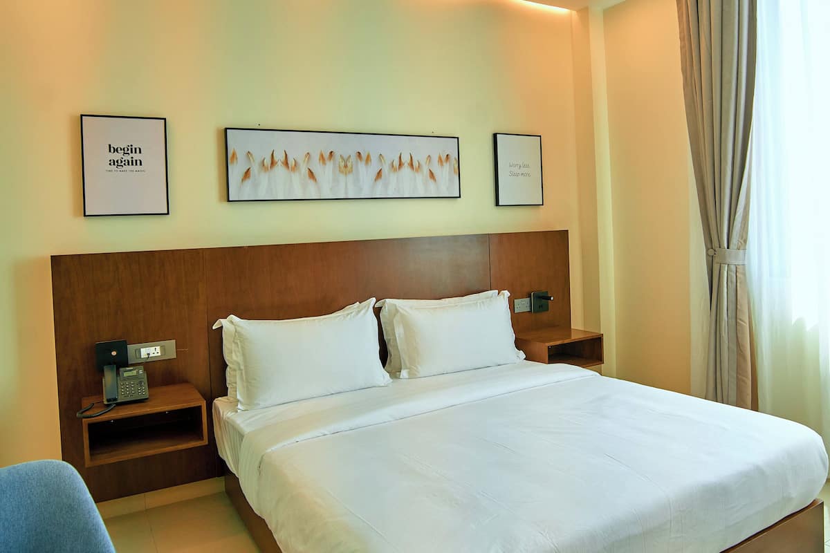 A hotel room with a large bed, bedside tables, a phone, and artwork on the wall.