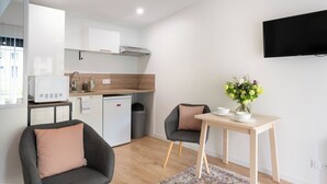 A modern kitchen with a microwave, sink, and a small refrigerator. There is a dining table with chairs and a vase of flowers.