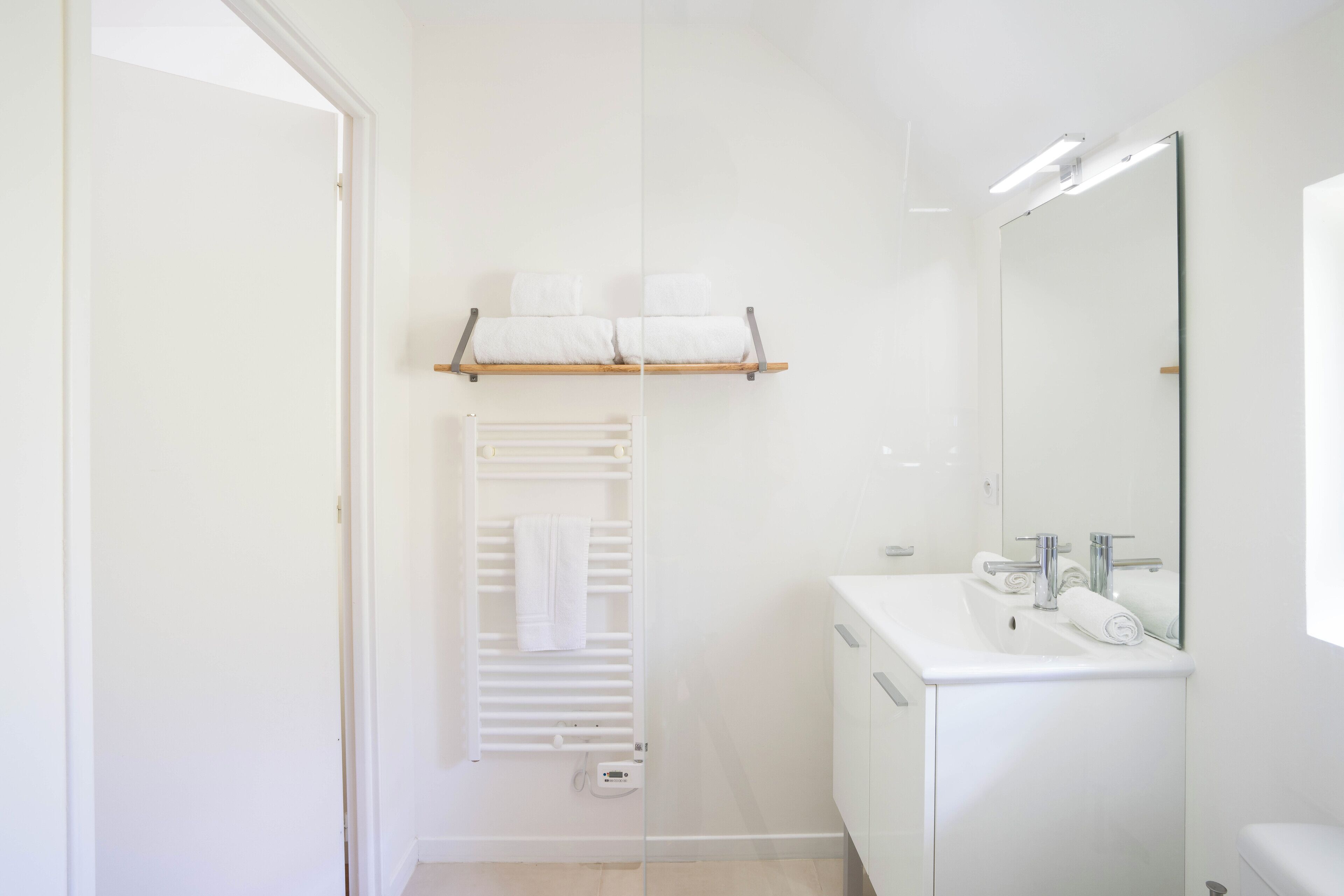 Une salle de bain moderne avec un lavabo blanc, un miroir et un porte-serviettes.