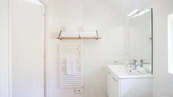 Un baño moderno con lavamanos, espejo y toallero blancos.