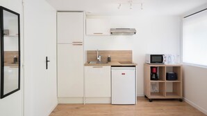 A compact kitchen with a refrigerator, microwave, sink, and a coffee maker on a shelf.