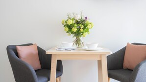 A dining table with two chairs, a vase of flowers, and white bowls and plates.