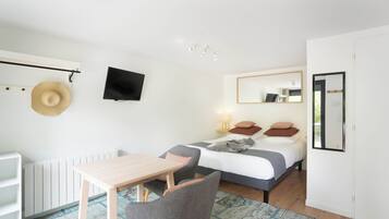 A bedroom with a bed, bedside table, chair, TV, and a radiator.