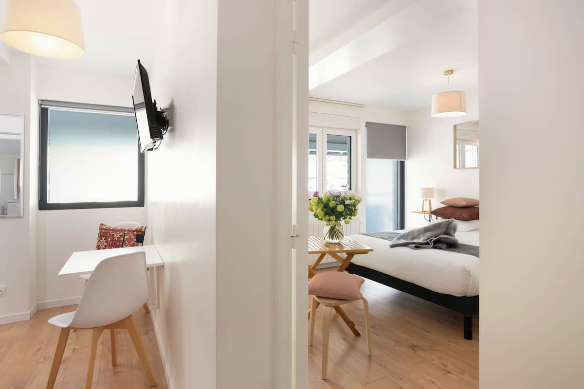 Un dormitorio moderno con cama, mesita de noche y escritorio con silla.