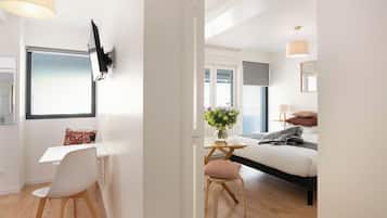 A modern bedroom with a bed, bedside table, and a desk with a chair.
