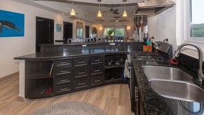 A modern kitchen with a curved island, built-in appliances, and pendant lighting. - Pelican Penthouse -mangrove Dock 3 Bedroom Home by RedAwning (Roatan)
