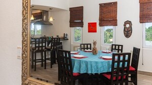 A dining area with a table set for four, surrounded by chairs, and a large mirror on the wall. - Pelican Penthouse -mangrove Dock 3 Bedroom Home by RedAwning (Roatan)