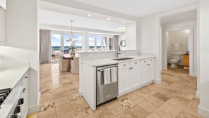 A modern kitchen with a central island, a built-in dishwasher, and a view of the ocean. - Retreat Steps from Sugar-White Sand (Watersound)