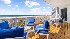 A wooden deck with blue chairs and a table, overlooking a beach. - Retreat Steps from Sugar-White Sand (Watersound)