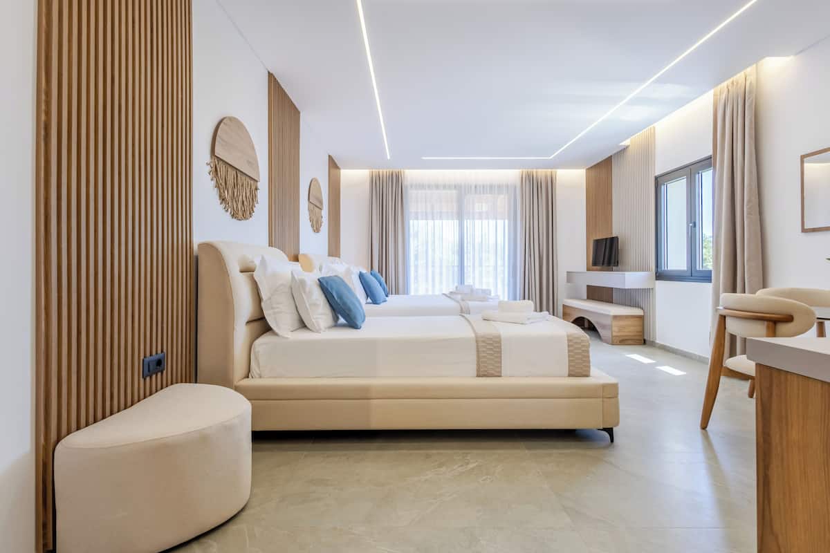 A modern hotel room with a large bed, a small seating area, a TV, and a desk.