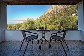 A balcony with two chairs and a table, overlooking a mountainous landscape. - Crystal Blue Hotel, Barbati (Corfu)