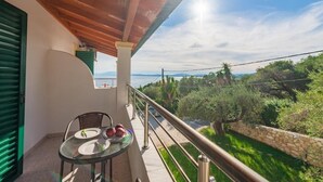 A balcony with a table and chairs, overlooking a scenic landscape with trees and a clear sky. - Crystal Blue Hotel, Barbati (Corfu)