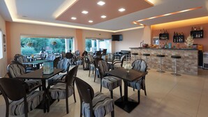 A restaurant with tables and chairs, a bar area, and a television mounted on the wall. - Crystal Blue Hotel, Barbati (Corfu)