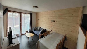 Una sala de estar acogedora con un sofá, una mesita redonda y un televisor.