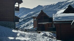 Un pueblo cubierto de nieve en la montaña, con edificios de madera y un cielo despejado.