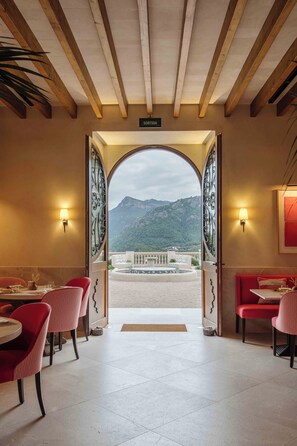 A restaurant with a view of mountains through an open archway. - Son Bunyola Hotel & Villas (Banyalbufar)