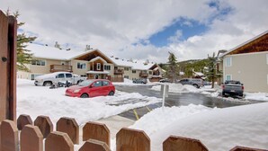 Un quartier résidentiel avec des maisons, des voitures garées et un sol recouvert de neige.