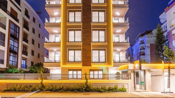 A multi-story hotel with a central atrium, balconies on each floor, and a well-lit facade. - Los Suites (Konyaalti)