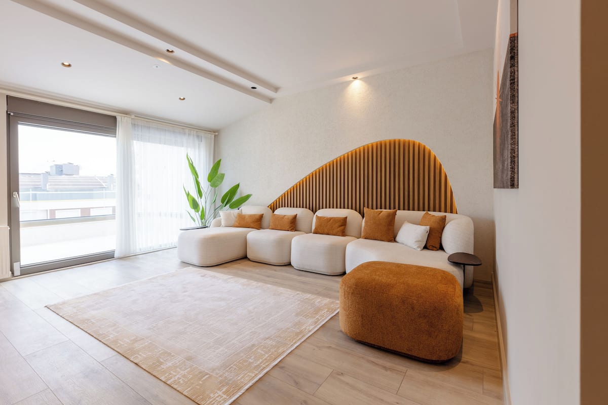 Uma sala de estar moderna com sofá seccional, tapete grande e planta em vaso.