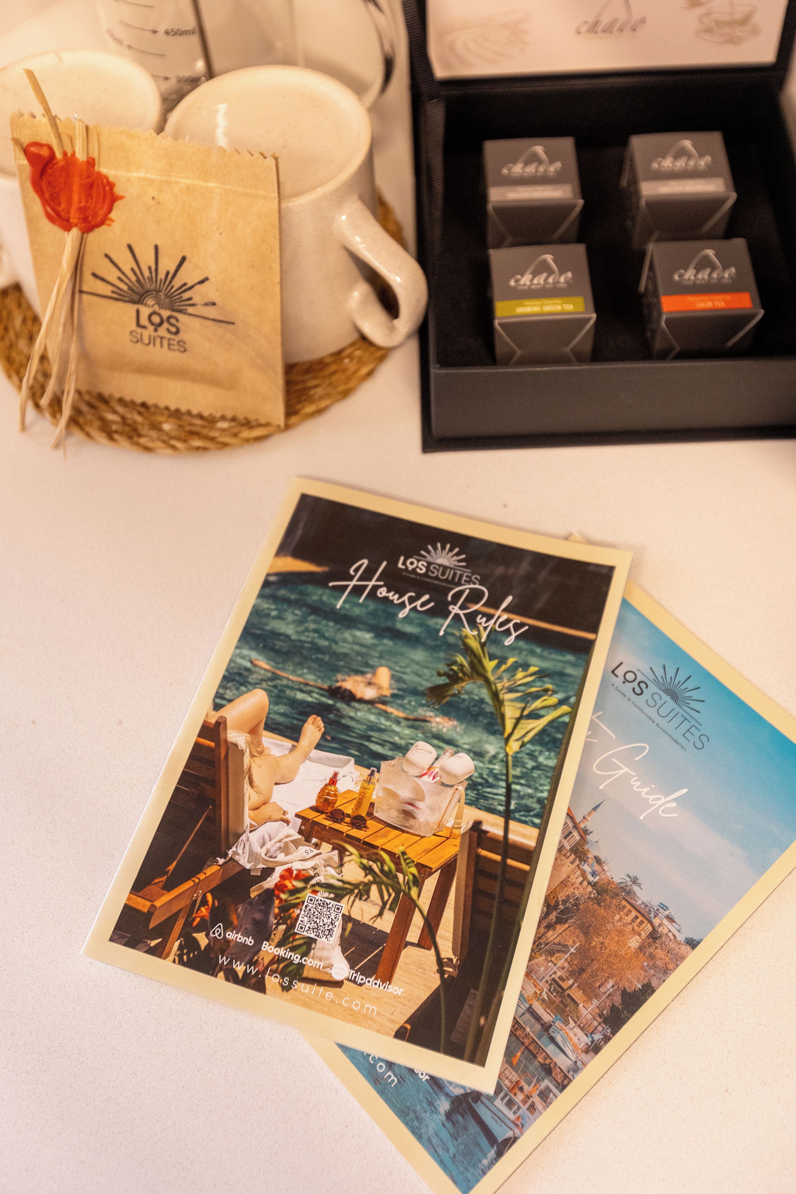 A Los Suites brochure, a coffee mug, a tea set, and a gift box.