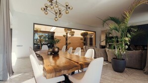 Un comedor moderno con una mesa de madera, sillas blancas y una planta grande en maceta.