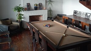 Ein Billardtisch mit Kugeln, ein Sofa, ein Esstisch und ein Blumentopf.