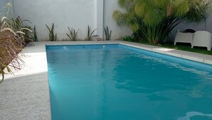 Ein rechteckiger Pool mit klarem, blauem Wasser, umgeben von einer Betonplattform.