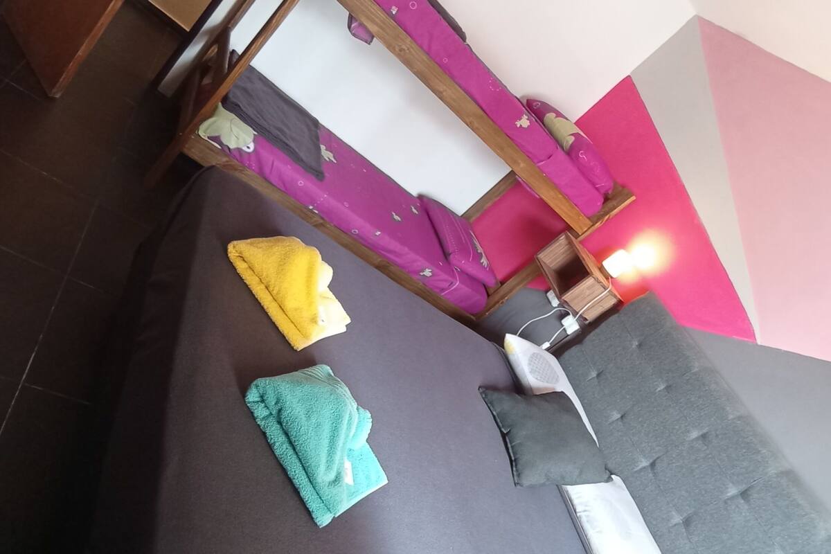 Ein Zimmer mit einem Etagenbett, einem kleinen Nachttisch und einer Wand in Rosa und Weiß.