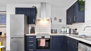 Une cuisine moderne avec des meubles de couleur bleu foncé, un réfrigérateur Bosch, un four Bosch, un lave-vaisselle Bosch et un four à micro-ondes.
