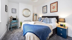 A bedroom with a bed, bedside table, lamp, and wall art. - Queens Mile 1 With Free Parking By My Getaways (Brighton)