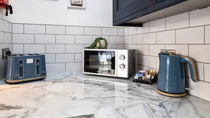 A kitchen with a toaster, a microwave, and a kettle on a marble countertop. - Queens Mile 1 With Free Parking By My Getaways (Brighton)
