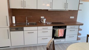 A modern kitchen with white cabinets, a stainless steel sink, a dishwasher, and a built-in oven.