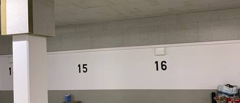 A parking garage with numbered parking spaces, concrete pillars, and a fluorescent light fixture.
