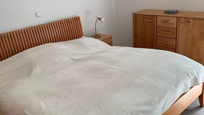 A bedroom with a wooden bed, a nightstand, a lamp, and a wooden dresser.