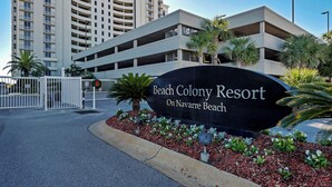 A sign for Beach Colony Resort with a parking garage in the background. - Soak Up The Sun - Beach Colony East PH 17C (Navarre)