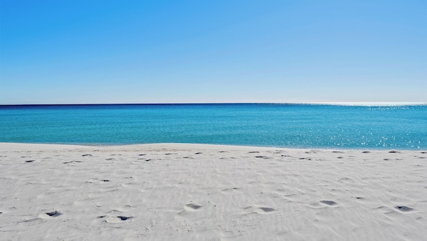 En strand med krystalklart, blåt vand og hvidt sand.