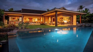 A modern house with a swimming pool, large windows, and outdoor seating.