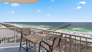Een balkon met uitzicht op het strand en de oceaan, met een tafel en stoelen.
