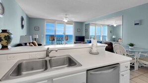 Een keuken met een groot eiland, een dubbele spoelbak en een eethoek met uitzicht op zee.