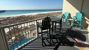 Un balcon avec vue sur la plage, une piscine et un espace salon extérieur.