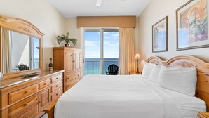 Une chambre d’hôtel avec un grand lit, une commode en bois et un balcon offrant une vue sur l’océan.