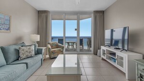 Una camera d'albergo moderna con un balcone, una TV a schermo piatto, un divano, un tavolino da caffè e una sedia.