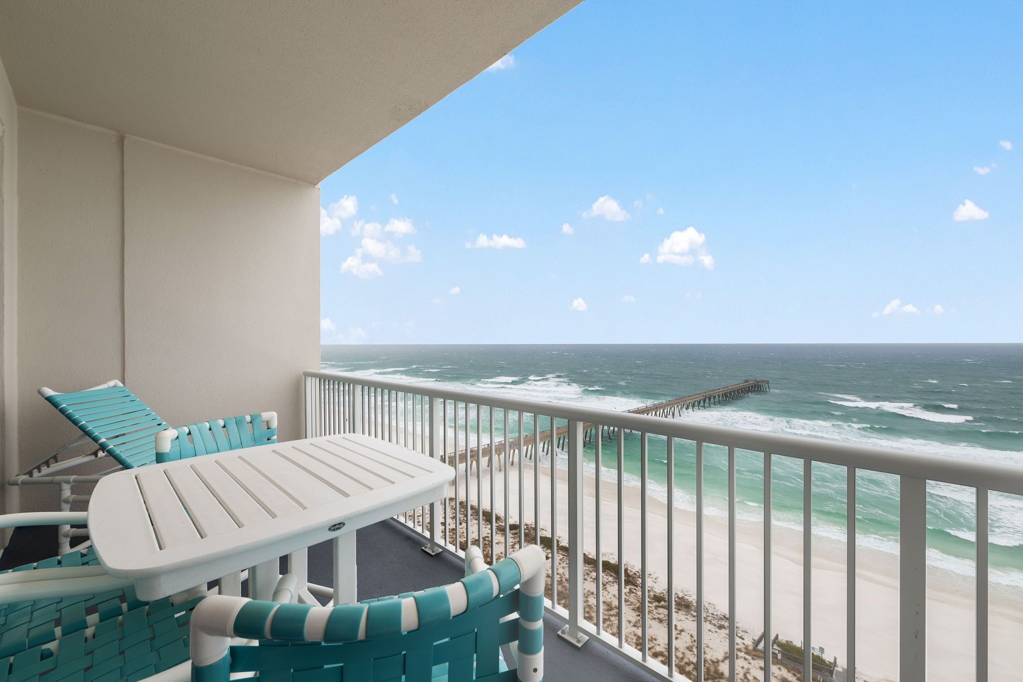A balcony with a view of the ocean and a pier.