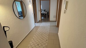 A hallway with a checkered rug, a round mirror, and a door leading to a dining area. - TOP Anbindung + Nähe Hannover + 2min Lehrte BHF (Lehrte)