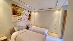 Un dormitorio moderno con dos camas, un cuadro grande en la pared y un diseño minimalista.
