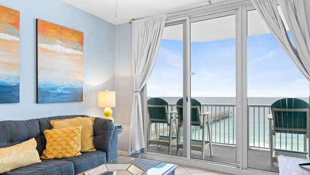 A room with a sofa, a coffee table, and a view of the ocean through a sliding glass door. - Slow M'Ocean - Summerwind 1302C (Navarre)