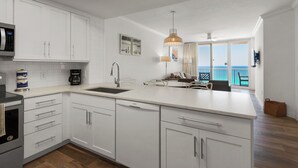 A modern kitchen with white cabinetry, a stainless steel sink, and a Bosch refrigerator. - Knot a Care- Summerwind 1102C (Navarre)